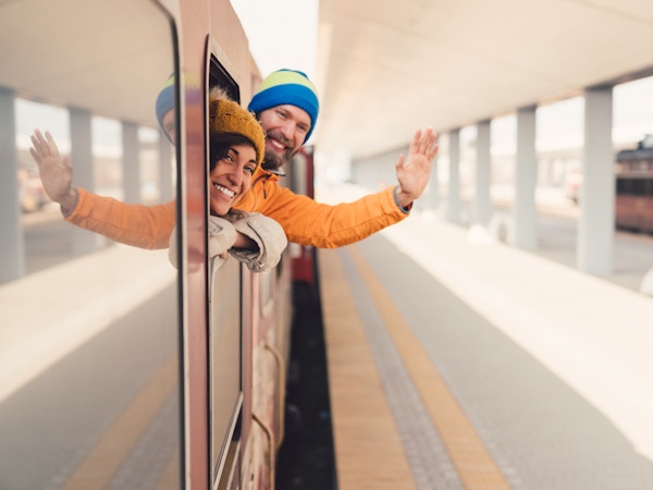 Ung mann med kjæreste som vinker med hånden fra toget