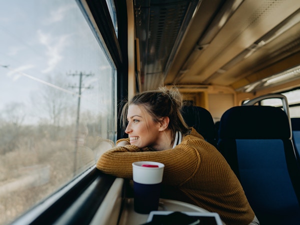 Bilde av en ung kvinne som rir på et tog og nyter turen mens hun ser gjennom vinduet