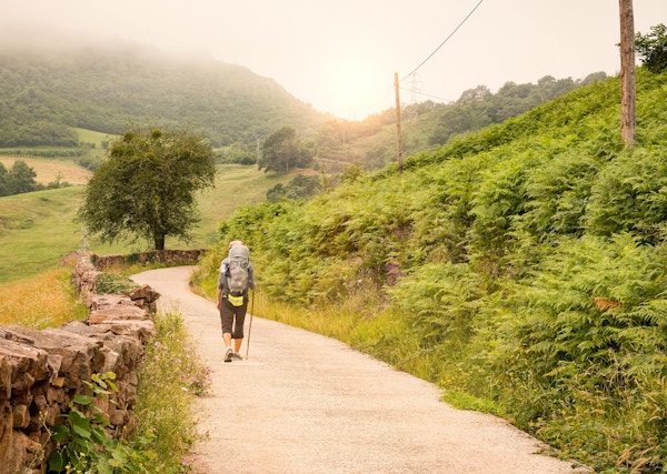 Pilegrim med ryggsekk som går Camino de Santiago i Spania.