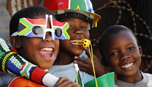 Tre afrikanske barn forbereder seg på å se verdensmesterskapet i fotball i Johannesburg, Sør-Afrika.