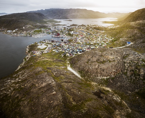 Qaqortoq, liten landsby på Grønland ved kysten. Luftfoto av hus i solnedgangen i en liten by ved kysten.