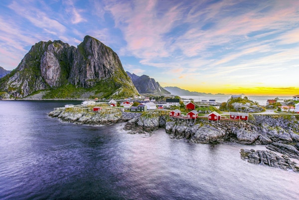 Populær utsikt over fiskehytter (rorbuer) i Hamnøy, Norge med Lilandstinden fjelltopp som bakgrunn under soloppgang