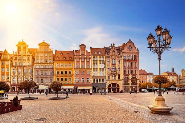 Sentrale markedstorg i Wroclaw Polen med gamle fargerike hus, gatelyslykt og vandrende turistpersoner ved nydelig fantastisk soloppgang om morgenens soloppgang. Reiseferiekonsept.