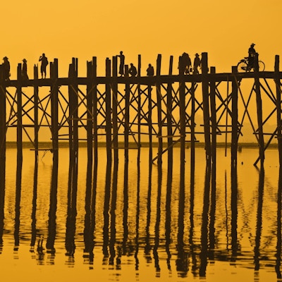 U Bein-broen ved solnedgang med mennesker som krysser elven Ayeyarwady, Mandalay, Myanmar