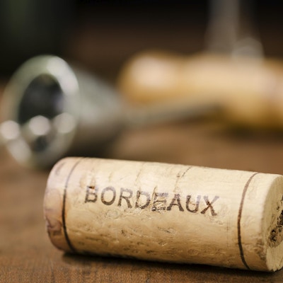 "En vinkork fra Bordeaux Frankrike med en korketrekker, vinglass og vinflaske i bakgrunnen."