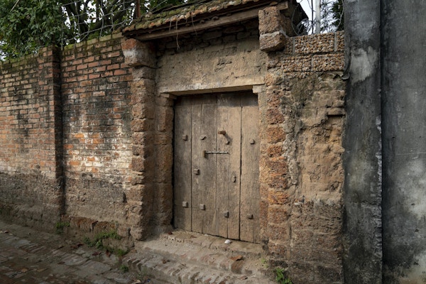 Inngangsparti til gammelt hus laget av murstein og lære. Foto.