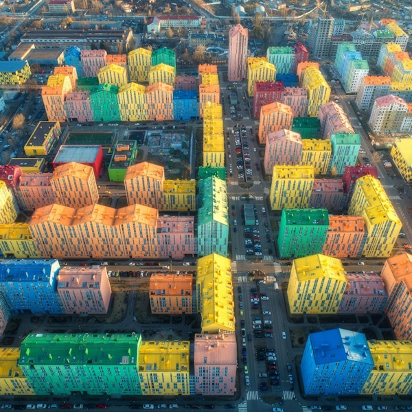 Luftfoto av de fargerike bygningene i den europeiske byen ved solnedgang. Bybilde med flerfargede hus, biler på gaten i Kiev, Ukraina. Topp utsikt. Urbant landskap. Flyfoto av sentrum