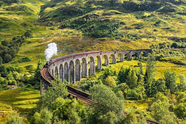 Glenfinnan Railway Viaduct i Skottland med damptog som passerer.