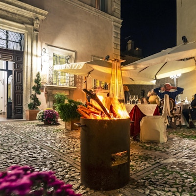 Folk som sitter ute om natten med en tønnebrann i forgrunnen, Hotel Antico Dimora alla Rocca i Trevi, Umbria