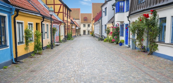 Brosteinsbelagt gate og fargerike hus i gamlebyen i Ystad, Sverige.