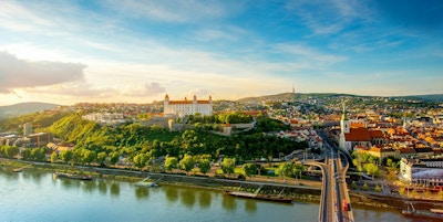 Bratislava flybilde med utsikt over gamlebyen med Saint-Martins katedral, slottshøyden og Donau-elven ved solnedgangen i Slovakia. Vidvinkel med kopieringsplass