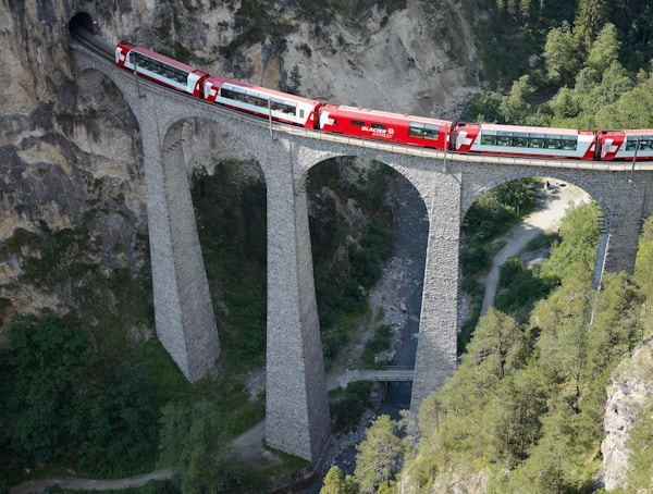 Glacier Express kjører over en høy bro inn i en tunnell.