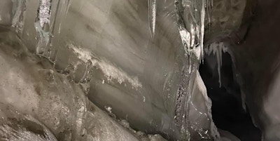 Nærbilde av istapper og snø i grotte.