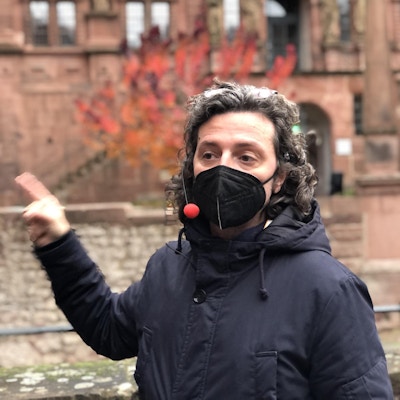 Mann med munnbinbd forteller om Heidelberg.