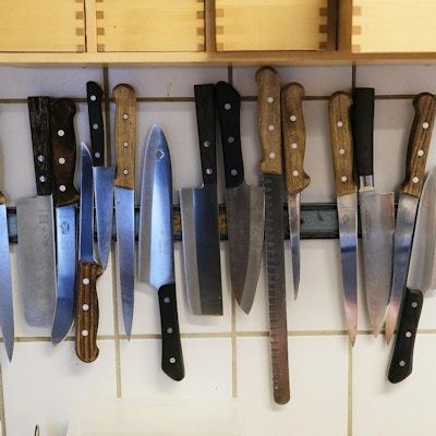 Samling med kniver henger på veggen i kjøkken.