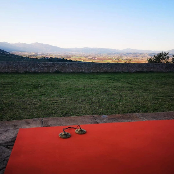 Yogamatte i forgrunnen og utsikt over landskap i med fjell i det fjerne.