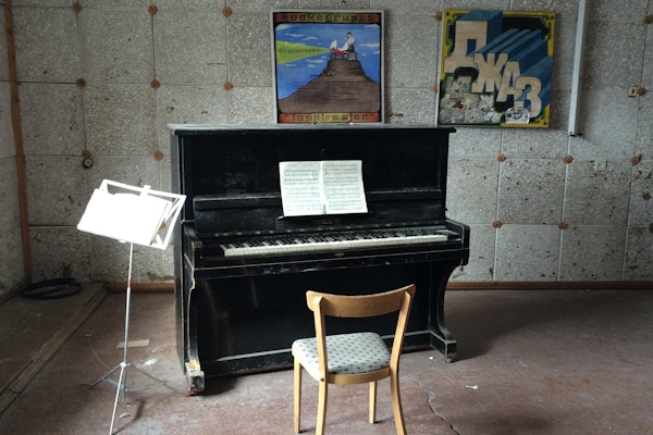 Forlatt piano med russiske bilder på veggen.