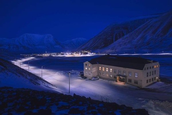Huset restaurant i snødekt landskap i polarnatten med utsikt mot byen
