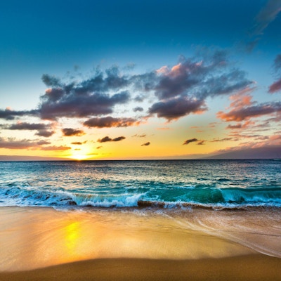 Solnedgang ved Kaanapali-stranden på vestkysten av øya Maui på Hawaii med øyene Lanai og Molokai i bakgrunnen. En vakker sandstrand, et populært turistmål på Hawaii. Fotografert i horisontalt format med lokasjon på Maui, Hawaii.