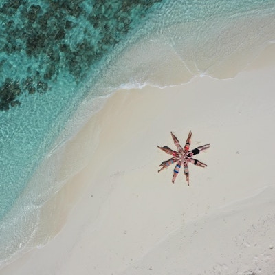 Mennesker på strand som ligger i sanden og danner en sjøstjerne