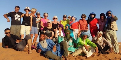 Et reisefølge i Sahara, Marokko. 21 mennesker smiler mot kamera i solen
