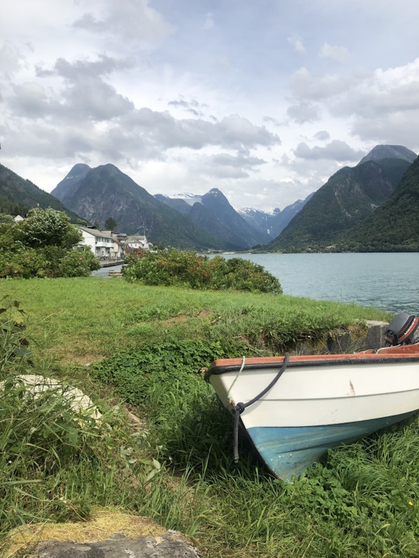 Liten båt på land med fjord og fjell i bakgrunnen