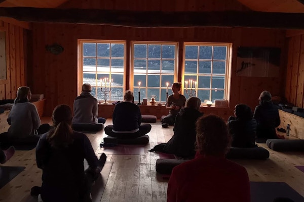 Folk gjør yoga i trehus ved fjorden.