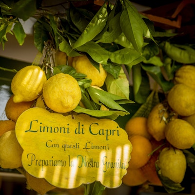 Sitroner med tekst "sitroner fra Capri øy. Fra disse sitronene tilbereder vi vår frosne dessert" skrevet på et skilt
