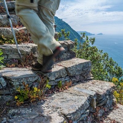 Steintrapp der en vandrer går oppover med utsikt over havet på ene siden
