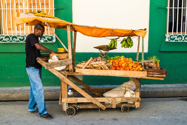 Santiago de Cuba, Cuba - 1. mars 2016: En mann selger frukt og grønnsaker lagt på et hjemmelaget mobil trestativ på gaten til Santiago de Cuba, Cuba, Latin-Amerika.
