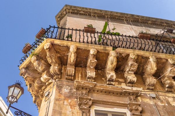 Del av fasaden på et bygg i Lecce, med steinfigurer under balkongen