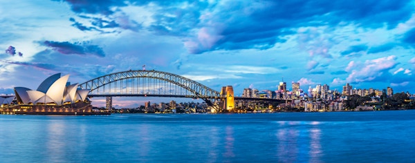 Solnedgang i Sydney med Harbour Bridge og Sydney operahus i bakgrunnen.
