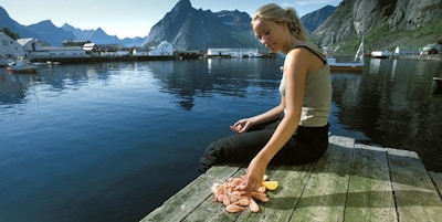 Kvinne spiser reker på brygga i Lofoten.