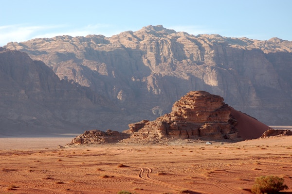 Kveldslandskap i Wadi Rum-ørkenen med kjøretøyspor i sanden.