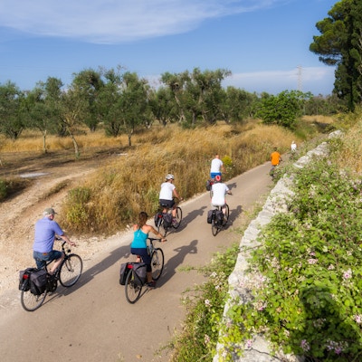 En gruppe mennesker sykler på landevei i Puglia