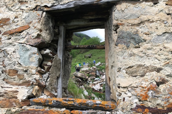 Fjellvandrere sett fra et vindu i en gammel steinhytte