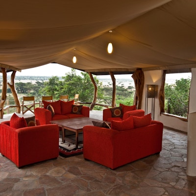 Lounge med røde mæbler og utsikt over savannen.