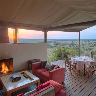 Lounge med dekket bort og utsikt til savannen i solnedgang.