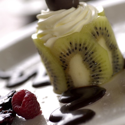 Nærbilde av dessert med krem, kiwi, bringebæær og sjokolade.