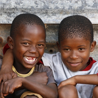 To unge afrikanske gutter som satt foran sin ydmyke hytte, rett utenfor Johannesburg, Sør-Afrika.