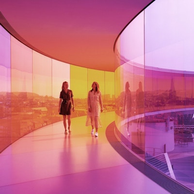 To kvinner går i regnbuefarget kunstinstallasjon.