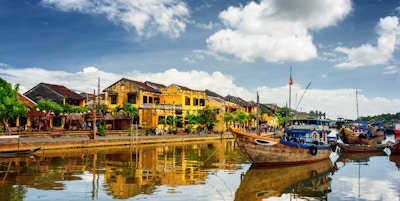 Trebåter på Thu Bon-elven i Hoi An Ancient Town (Hoian), Vietnam. Gule, gamle hus ved vannkanten er reflektert i elven. Hoi An er et populært turistmål i Asia.