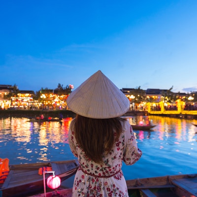 Kvinneturist er på sightseeing ved elven Thu Bon og bruker Non La (vietnamesisk hatt) i Hoi An, Vietnam.