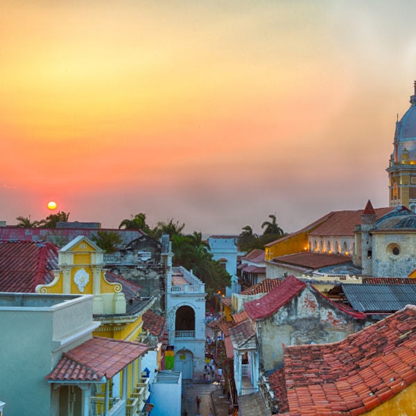 Utsikt over hustakene i den gamle byen Cartagena under en levende solnedgang. Spiret til Cartagena katedral står høyt og stolt.