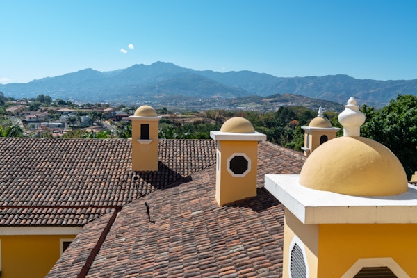 Ser over hustakene i San Jose Costa Rica ved foten av fjellene. I forgrunnen er fargede kupler.