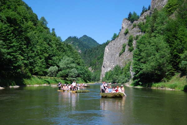 Tradisjonelle treflåter glir nedover en elv med fjell i bakgrunnen