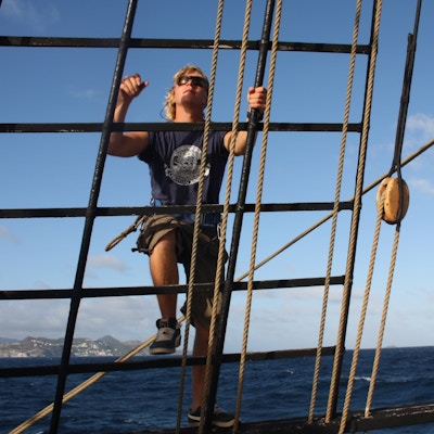 en mann klatrer opp til seilet