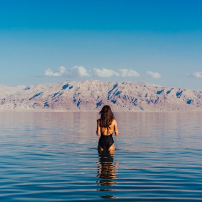 Jenta slapper av og svømmer i vannet i Dødehavet i Israel