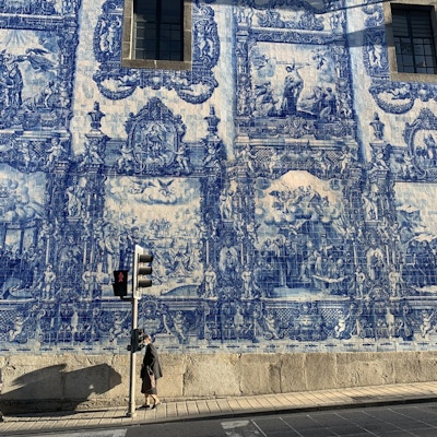 Gate med husvegg med blå og hvite fliser som illustrerer religiøse motiver.