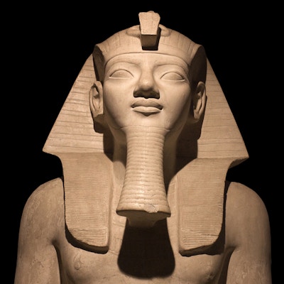 Detalj av sittende egyptiske faraostatue isolert på svart bakgrunn